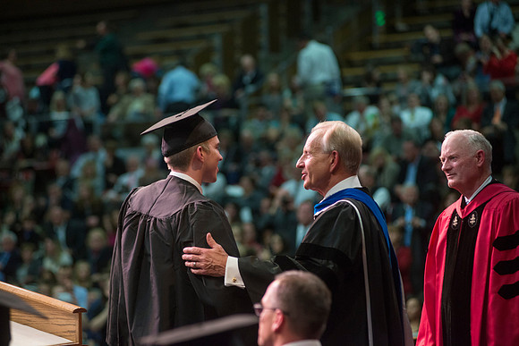 Elder W. Craig Zwick and President Kim B. Clark award diploma covers to graduates in the College of Business and Communication.