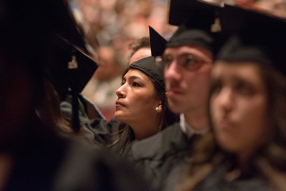 A student listens to speakers at the Brigham Young University-Idaho commencement ceremony with her fellow peers. Photo by Ryan Chase