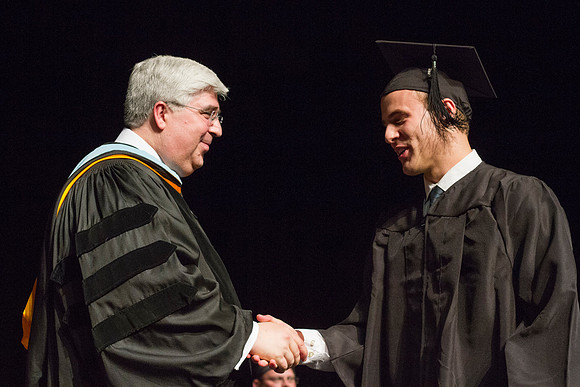 Elder Teixeria of the Europe Area Presidency congratulates a graduate during the Convocation of the College of Business and Communication in the Hart Auditorium.