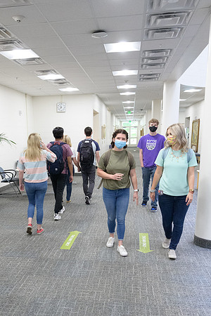 Student volunteers show the way to stay safe during this COVID 19 pandemic by social distancing, following pathway arrows and proper wearing of masks .