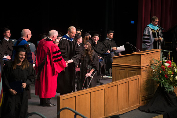 Elder W. Craig Zwick and President Kim B. Clark award diploma covers to graduates in the College of Business and Communication.
