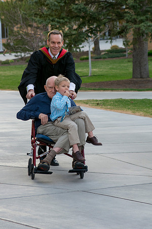 Faculty member pushes his father and son in a wheelchair around campus. Photo by Ryan Chase