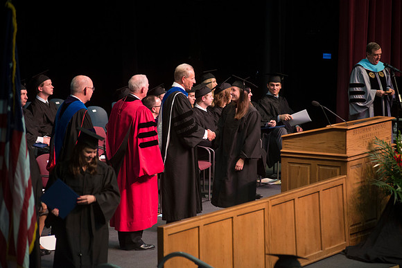 Elder W. Craig Zwick and President Kim B. Clark award diploma covers to graduates in the College of Business and Communication.
