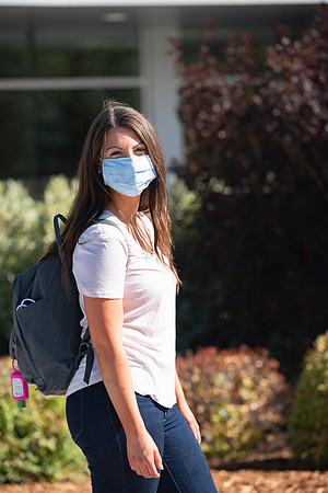 Examples of students staying safe and healthy during the COVID-19 pandemic by social distancing, following pathway arrows, and wearing face masks.