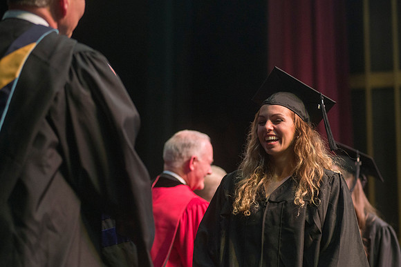 Elder W. Craig Zwick and President Kim B. Clark award diploma covers to graduates in the College of Business and Communication.