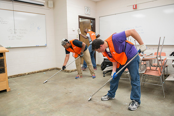 Workers remove glue residue from the carpet removal.