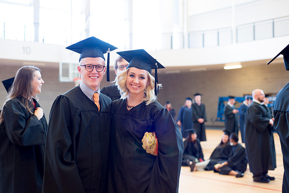 Graduates wait inside the gym area preparing to enter Commencement ceremony.