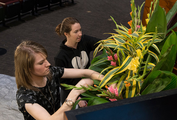 Floral Design students, Lauren Smith and Margaret Setterstrom create a beautiful floral arrangement in front of the podium for devotional.