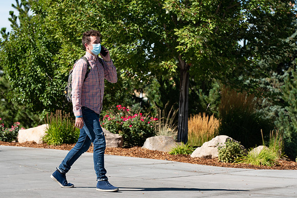 Examples of students staying safe and healthy during the COVID-19 pandemic by social distancing, following pathway arrows, and wearing face masks.