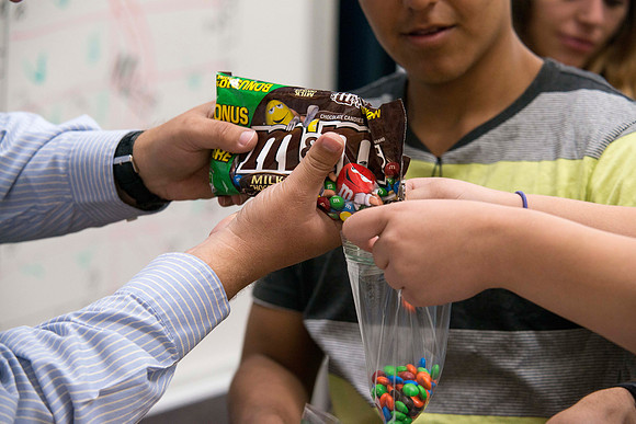 Brother Adamson hands out M&amp;M's to his Political Science students during class as part of a hands-on activity,