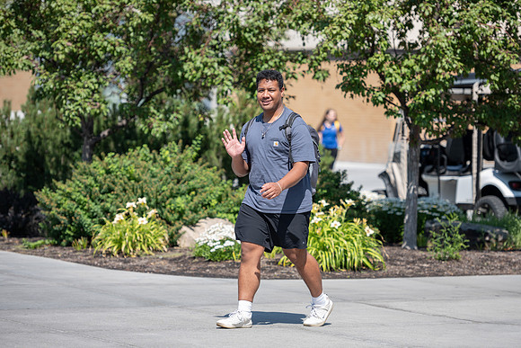 Student waving to the camera outside the Manwaring Center