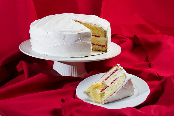 A moist vanilla cake topped with creamy frosting and filled with raspberries.