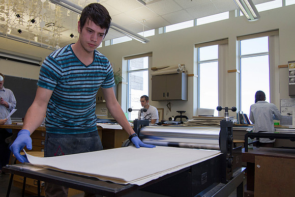 A student in Sister Jimison's Printmaking class, prepares to use the press for an assignment.