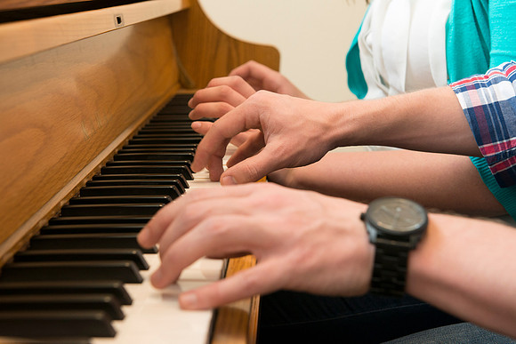 Students practice playing the piano for the new housing promo pictures.