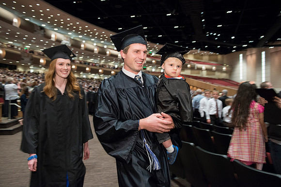 Graduates gather and march in during the processional for April 2014 Graduation ceremonies in the BYU-Idaho Center. Steven Davis with his wife and son.