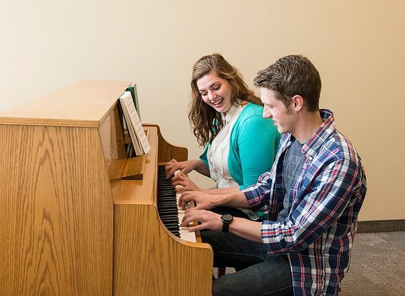 Students practice playing the piano for the new housing promo pictures.
