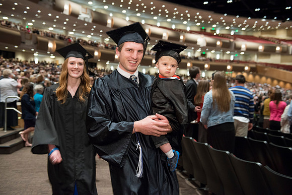 Graduates gather and march in during the processional for April 2014 Graduation ceremonies in the BYU-Idaho Center. Steven Davis with his wife and son.
