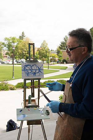 Brother Bodily talks to his students about the painting demonstration he is giving outside the Spori Building.