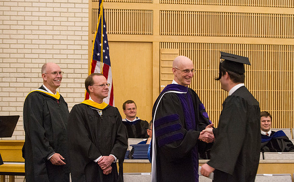 Advancement Vice President Henry J. Erying shakes hands with a graduate during Convocation in the Taylor Chapel.