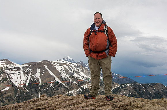 Jackson Hole Ski area. Scouting out Rock Spring Buttress for video shoot. Michael Ballard on top with the Grand in the background. Views from the top of the Ski Resort via the Aerial Tram