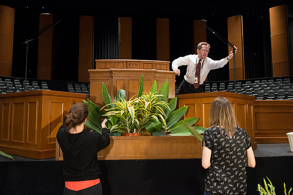 Spencer Allen sets up the teleprompters for devotional while Floral Design students create a beautiful floral arrangement in front of the podium for devotional each week.
