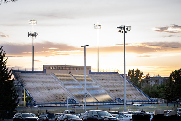 The stadium during sunset with people going up and down the bleacher stairs