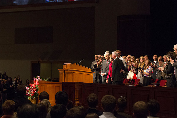 President Kim B. Clark and his wife, Sue, hold onto each other as Elder Russell M. Nelson steps back from the podium to give appreciation for their service. The student body and staff give a round of