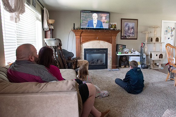 Brenna Bushman, a student in the special ed program, sits with her family and watches the devotional from Elder and Sister Renlund.