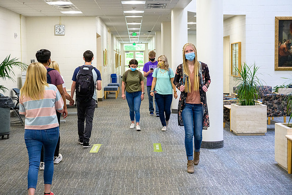 Student volunteers show the way to stay safe during this COVID 19 pandemic by social distancing, following pathway arrows and proper wearing of masks .