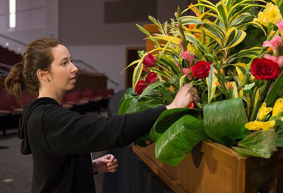 Floral Design students, Lauren Smith and Margaret Setterstrom create a beautiful floral arrangement in front of the podium for devotional.