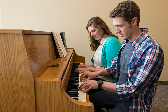 Students practice playing the piano for the new housing promo pictures.