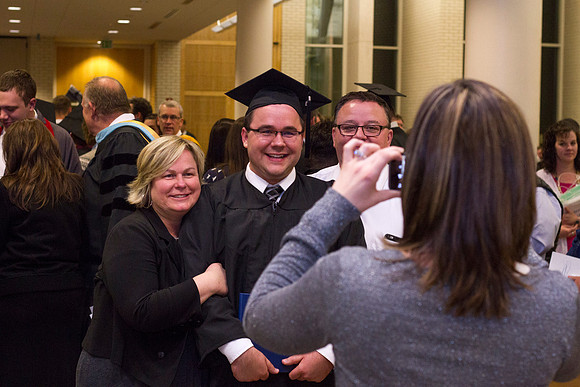 A graduate poses with his family after Convocation in the Taylor Chapel.