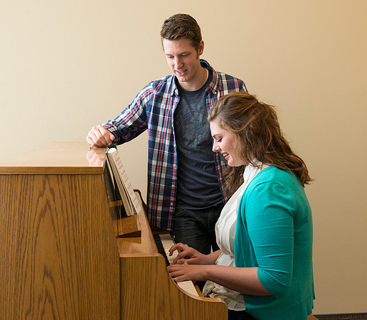 Students practice playing the piano for the new housing promo pictures.