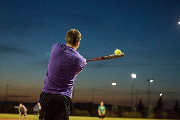 A BYU-I student swings at the ball during a recreational softball game.