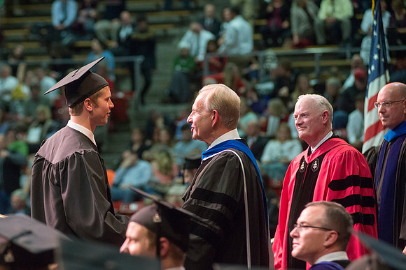 Elder W. Craig Zwick and President Kim B. Clark award diploma covers to graduates in the College of Business and Communication.