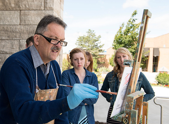 Brother Bodily gives a painting demonstration during his Oil Painting class outside the Spori Building.