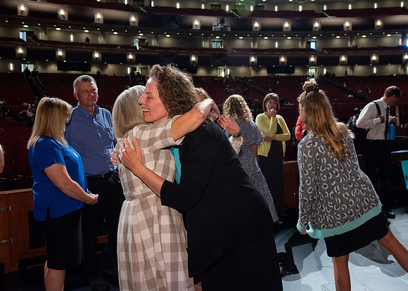 Sister Heather Hall huging her family after devotional.