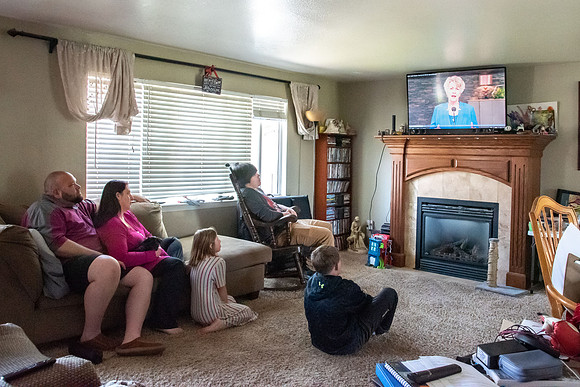 Brenna Bushman, a student in the special ed program, sits with her family and watches the devotional from Elder and Sister Renlund.
