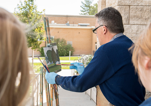 Brother Bodily gives a painting demonstration during his Oil Painting class outside the Spori Building.