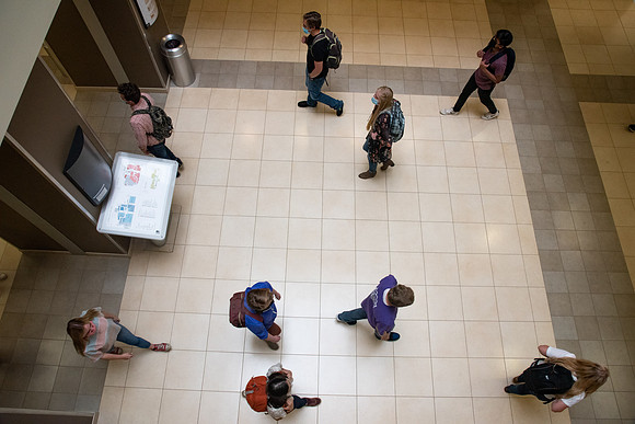 Examples of students staying safe and healthy during the COVID-19 pandemic by social distancing, following pathway arrows, and wearing face masks.