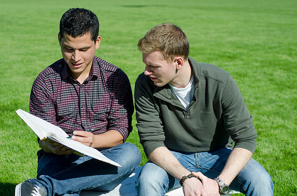 Two friends study outside in the sun.