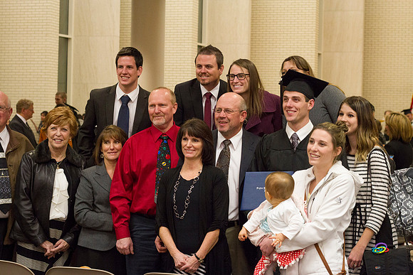 A graduate poses with his family after Convocation in the Taylor Chapel.