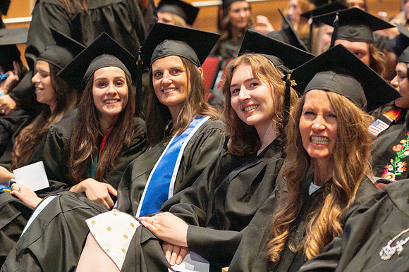 Brother Timothy Rarick laughs with graduates during convocation for the College of Education & Human Development