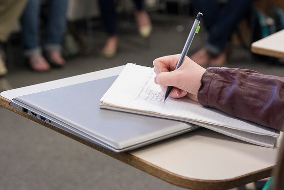 A student takes notes in Brother Robert's Sociology class during the 2014 Spring Semester.