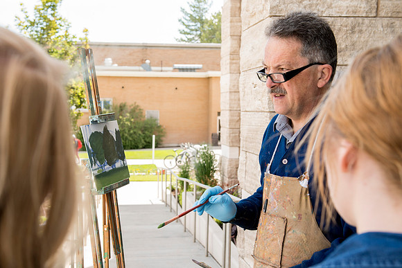 Brother Bodily gives a painting demonstration during his Oil Painting class outside the Spori Building.