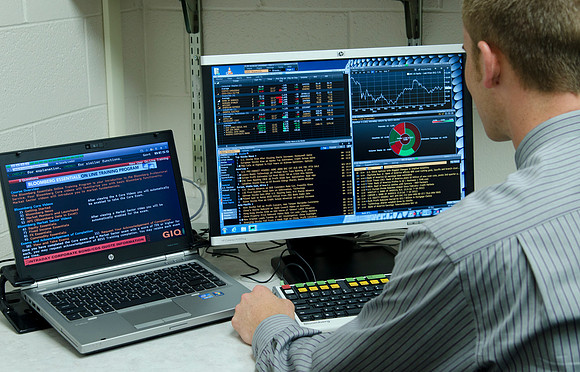 Juan Whiting sitting at the Bloomberg terminal.  A powerful program which allows students to research financial information in a fraction of the time allowing more time for analysis.