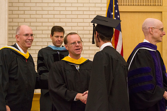 A graduate shakes hands with Eric B. Karl, Dean of College of Physical Sciences and Engineering in the Taylor Chapel during Convocation.