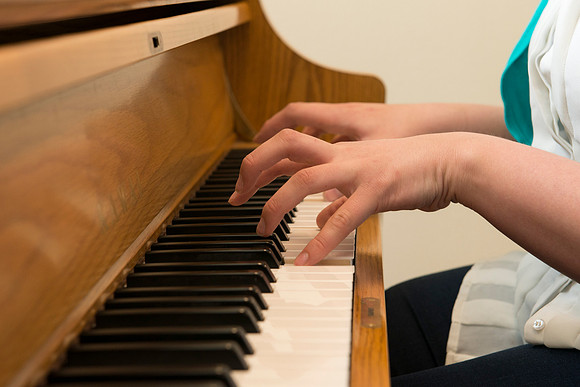 Students practice playing the piano for the new housing promo pictures.