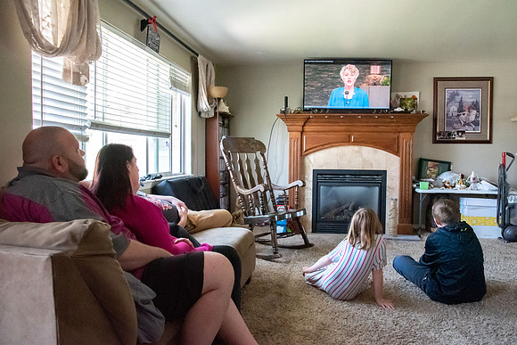 Brenna Bushman, a student in the special ed program, sits with her family and watches the devotional from Elder and Sister Renlund.