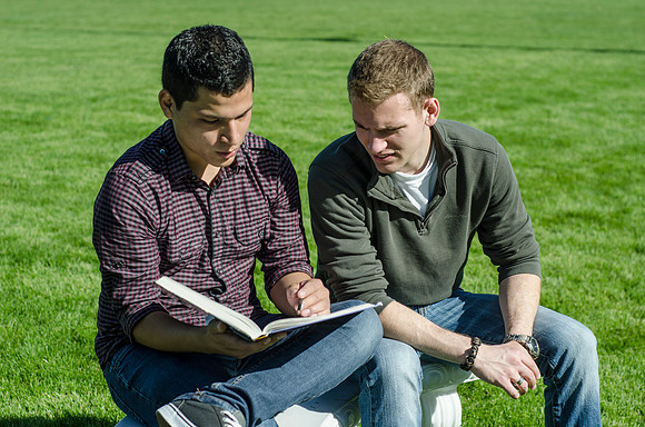 Two friends study outside in the sun.